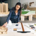 african-american-woman-with-model-house-table-near-safety-helmet-equipments