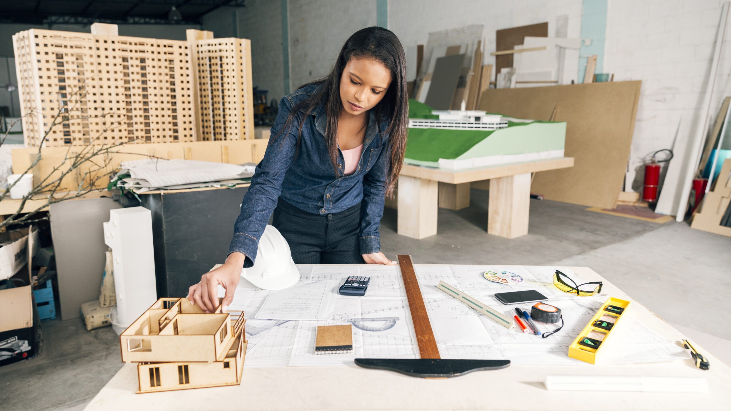 african-american-woman-with-model-house-table-near-safety-helmet-equipments