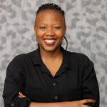 Larona Lekgobe, A black woman smiling while folding her arms. She is wearing a black shirt.